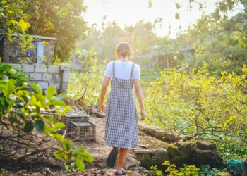 Home composting setup with a woman turning soil in a backyard bin
