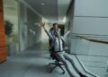 Woman practising breathing techniques in a quiet office hallway before a meeting
