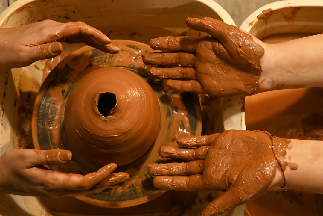 Hands shaping a clay bowl while starting a pottery hobby at home