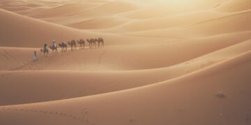 Foto de planificación de viaje al Sahara, prepara tu equipaje y reserva con cabeza 1 - MAwebzine Viajero en camello durante un viaje por el Sahara cruzando las dunas de Erg Chebbi